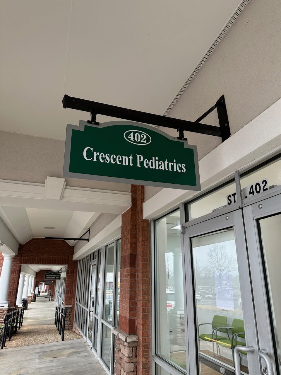 A sign for crescent pediatrics is hanging from the ceiling of a building.