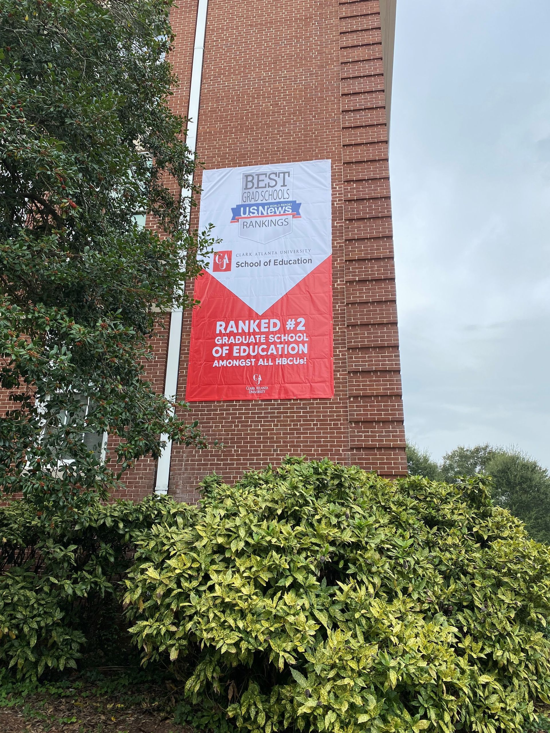 A red and white banner is hanging on a brick building