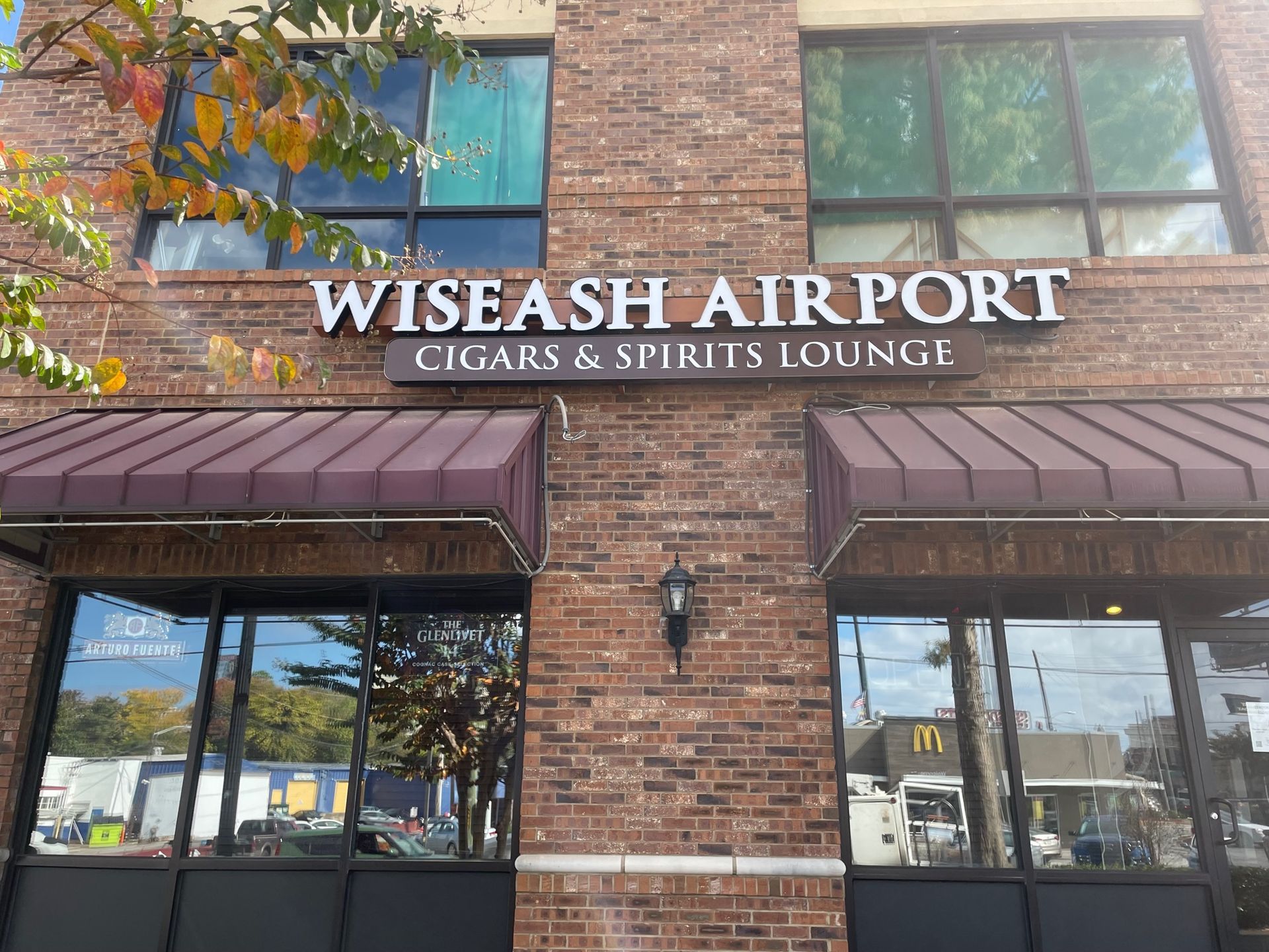A brick building with a sign that says wiseash airport cigars & spirits lounge.