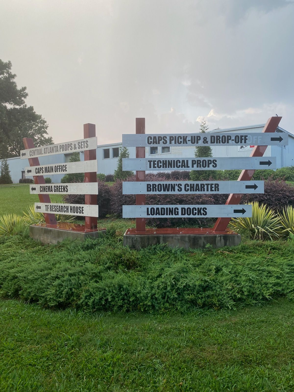 A bunch of signs are sitting in the grass in front of a building.