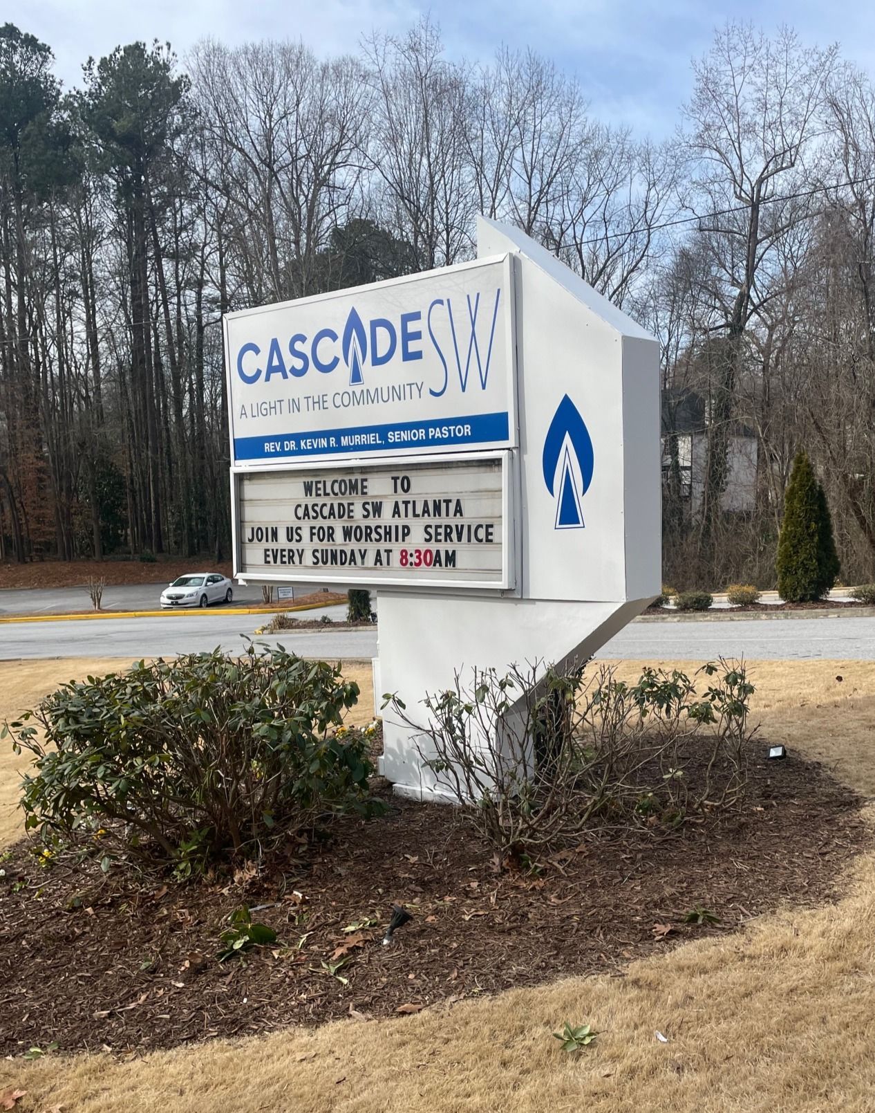 A sign for cascades church is sitting on the side of the road.