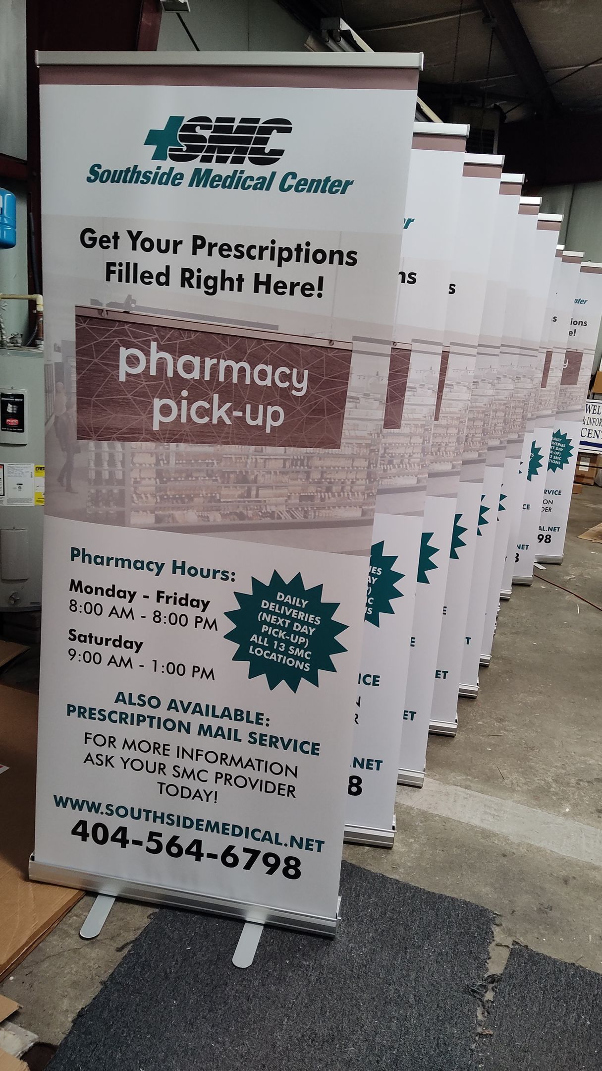 A row of pharmacy pick up signs are lined up in a warehouse.