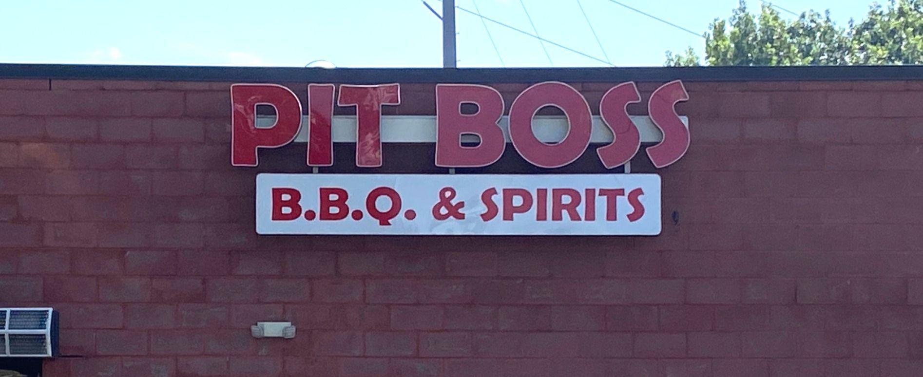 A pit boss bbq and spirits sign on a brick building