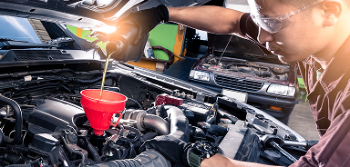 Man pouring oil into vehicle in garage | Seehorn Tire