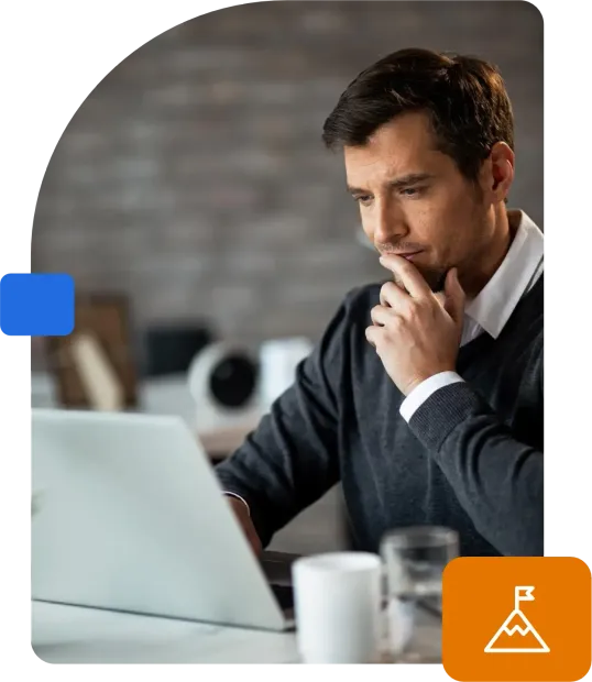 Um homem está sentado em uma mesa usando um laptop.