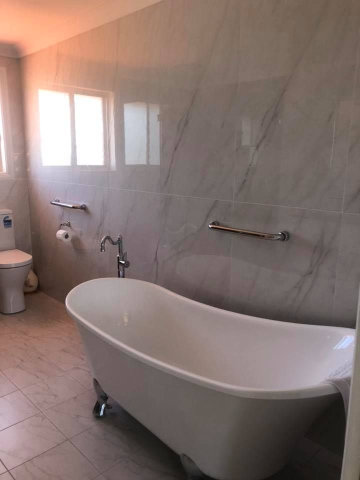 A Bathroom with A Bathtub, Toilet and Window — Alcando Renovations & Maintenance In Old Bar, NSW