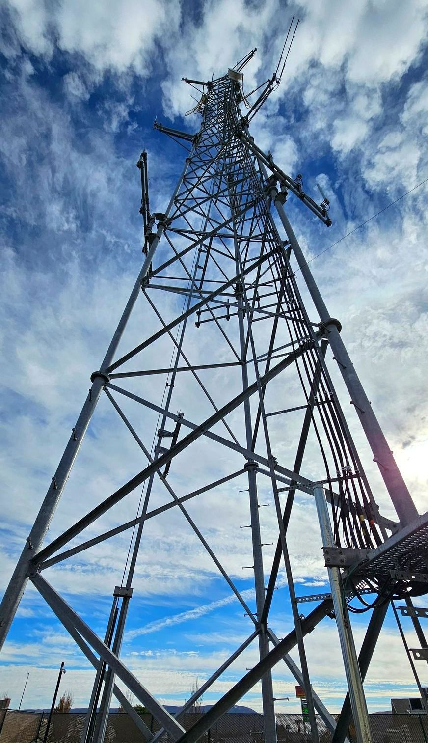 A telephone pole with a bunch of antennas on it in the middle of a field.