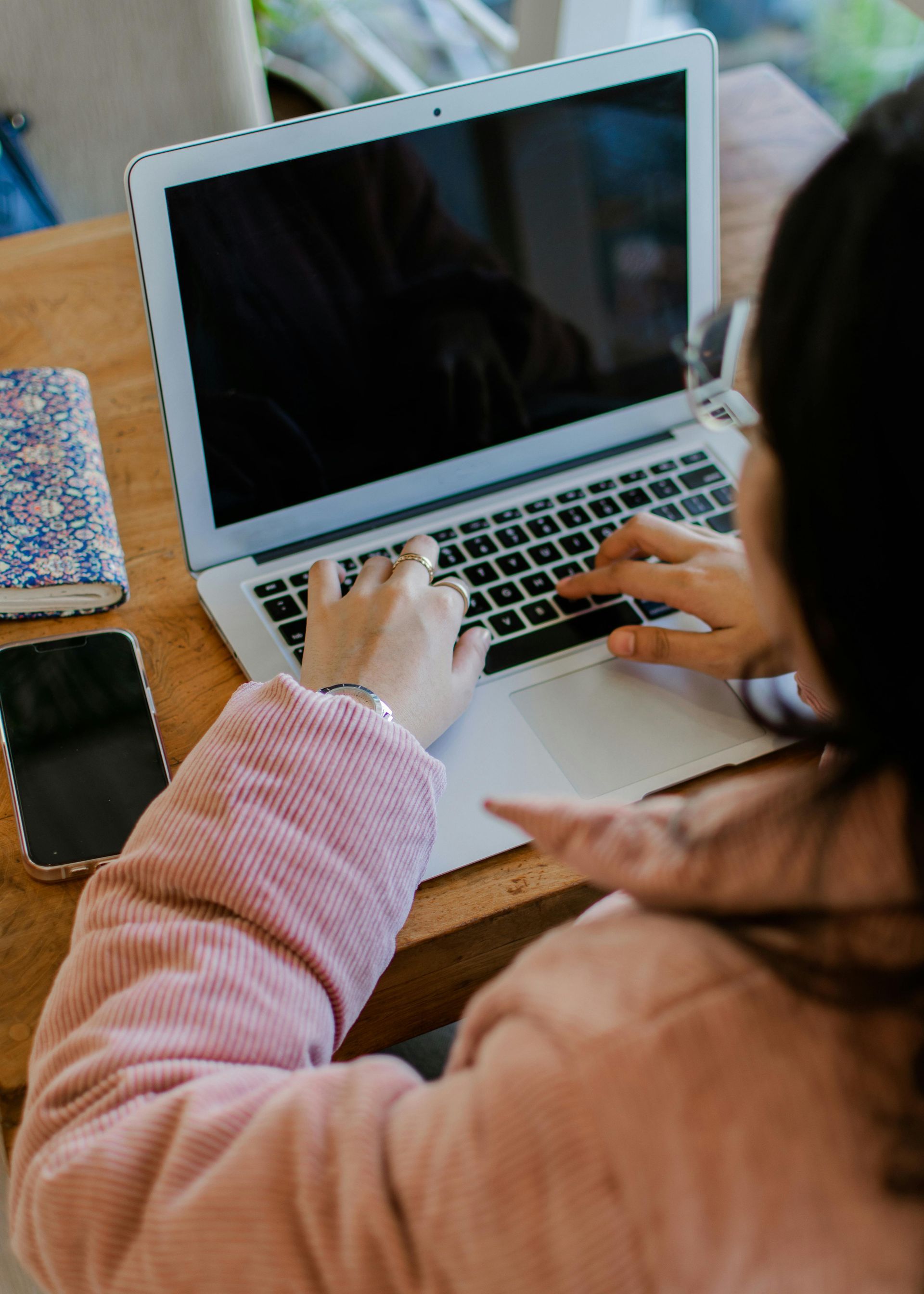 A woman is typing on a laptop computer while sitting at a table.