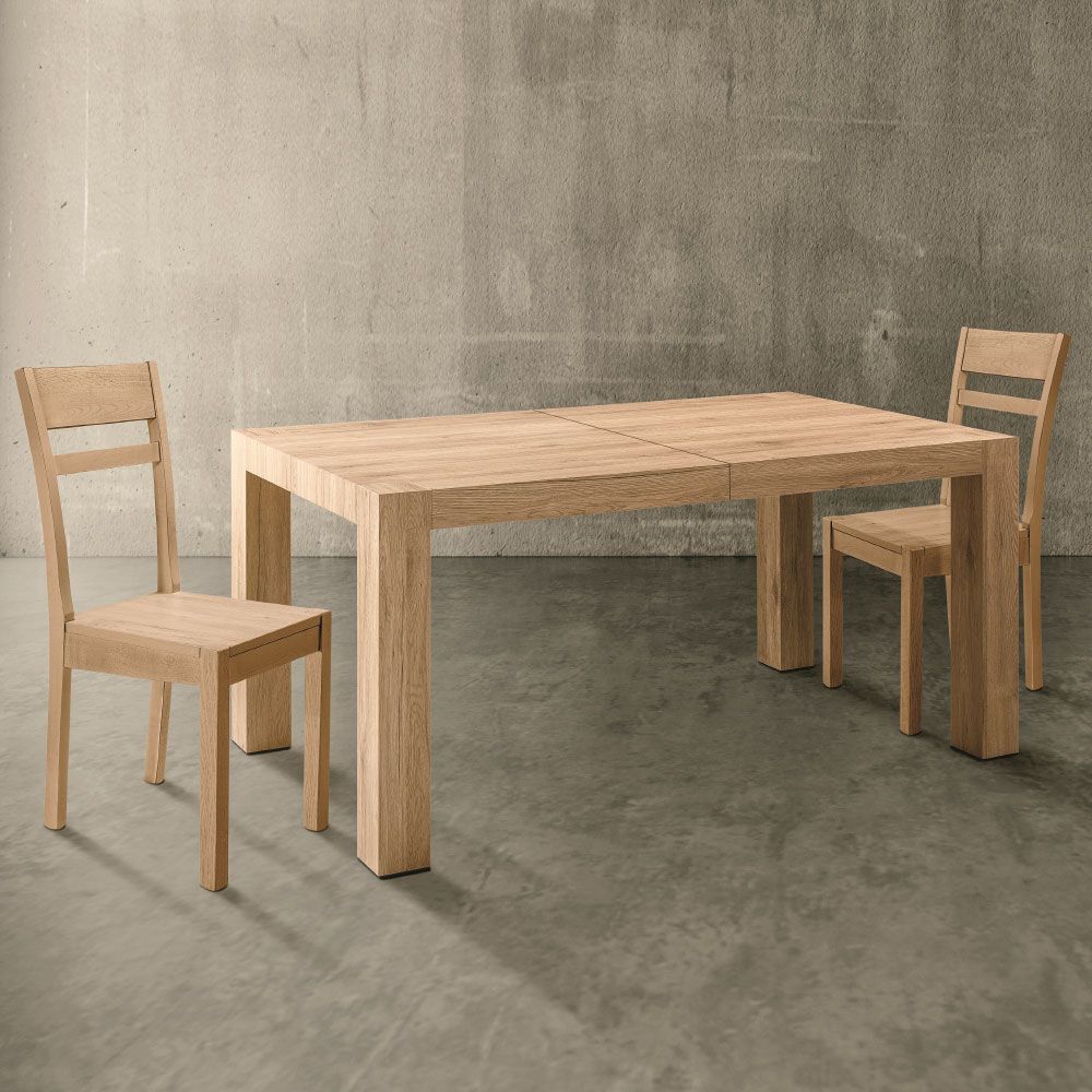 Tavolo da pranzo in legno e due sedie di fronte a un muro di cemento.