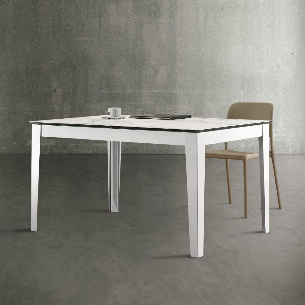 Un tavolo quadrato bianco con una sedia beige di fronte a una parete grigia. Sul tavolo c'è una tazza da caffè.