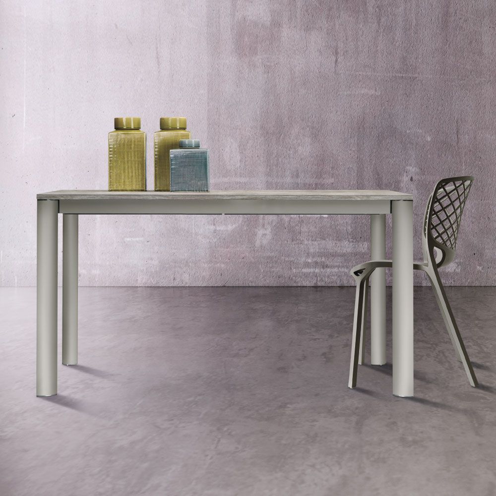 Un tavolo con barattoli decorativi e una sedia contro una parete grigia screziata.