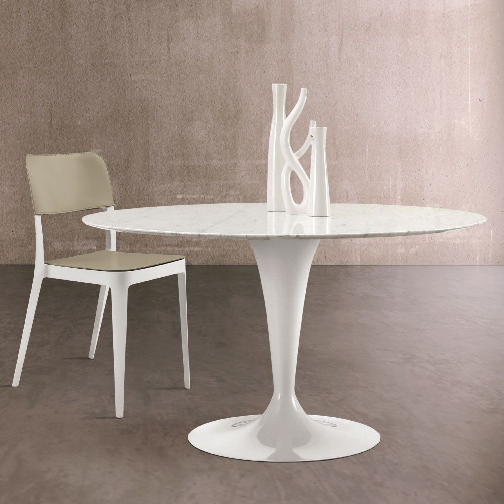 Tavolo ovale bianco in stile tulipano con piano in marmo, vasi bianchi e una sedia color cuoio in una stanza.