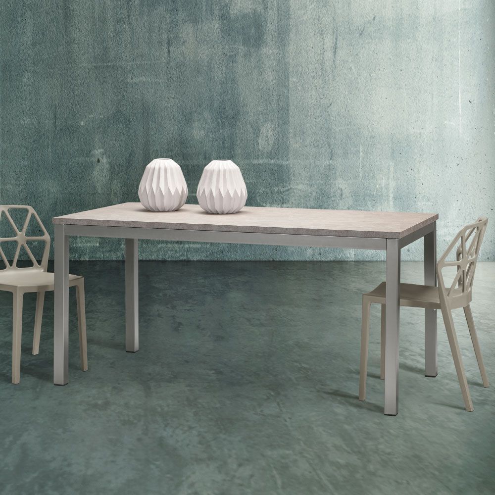 Un tavolo rettangolare con due sedie, due vasi contro una parete con texture color verde acqua.