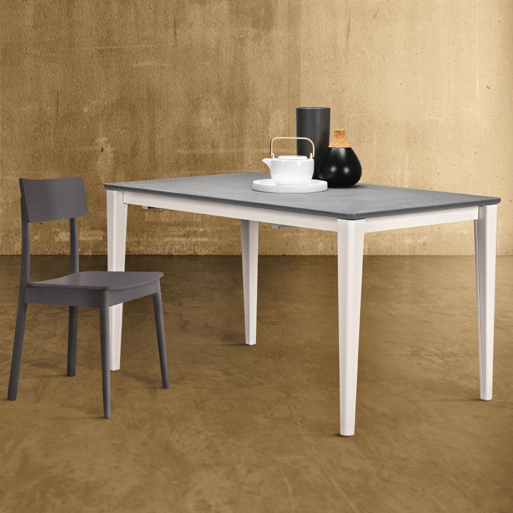 Scena di una sala da pranzo con un tavolo grigio, gambe bianche e una sedia grigia.