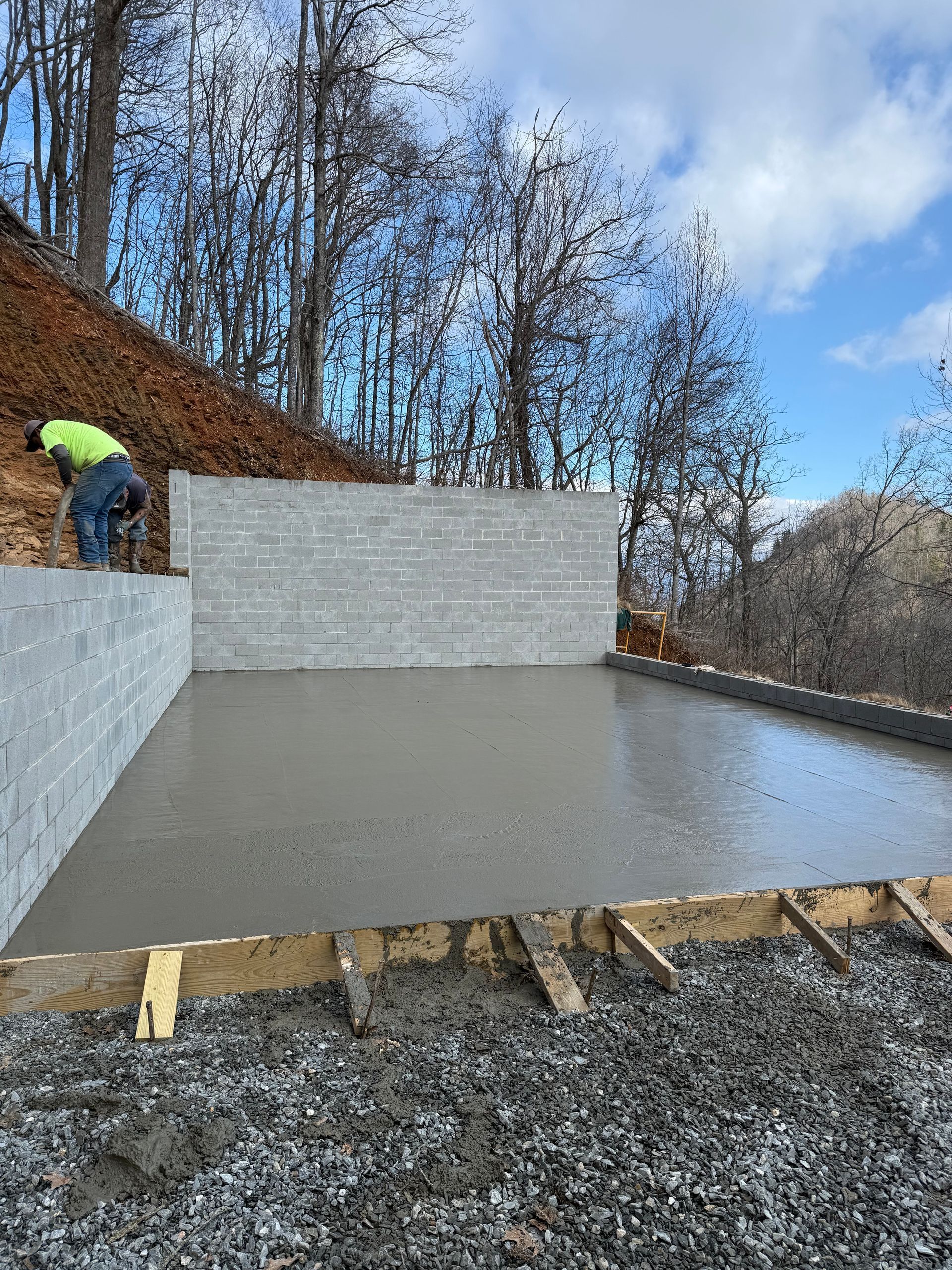 Stone fireplace in a cabin with windows and wooden walls.