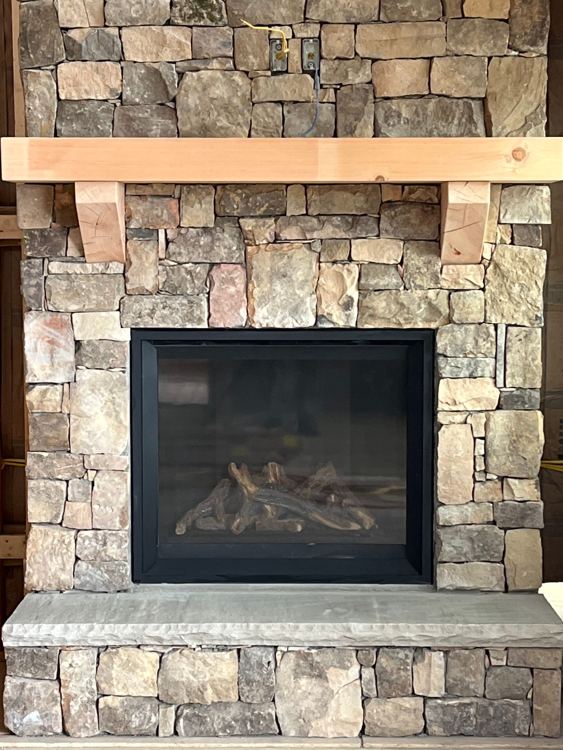 New concrete driveway being poured near a house with a stone facade, wooden stairs, and a mountain view.