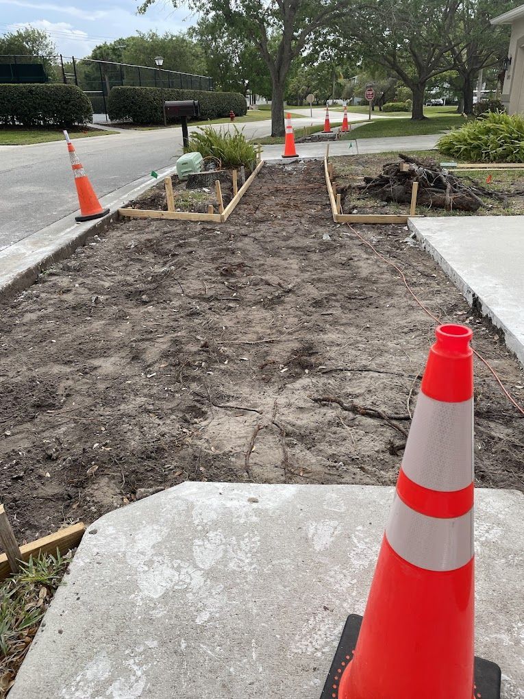 A row of orange and white traffic cones are sitting on a sidewalk.