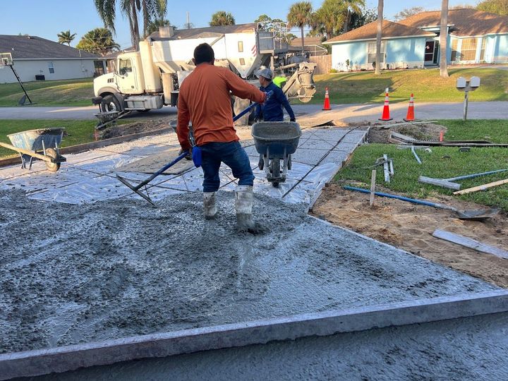 A man is pushing a wheelbarrow full of concrete.