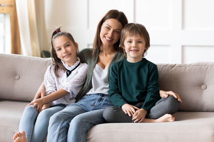 A woman and two children are sitting on a couch.