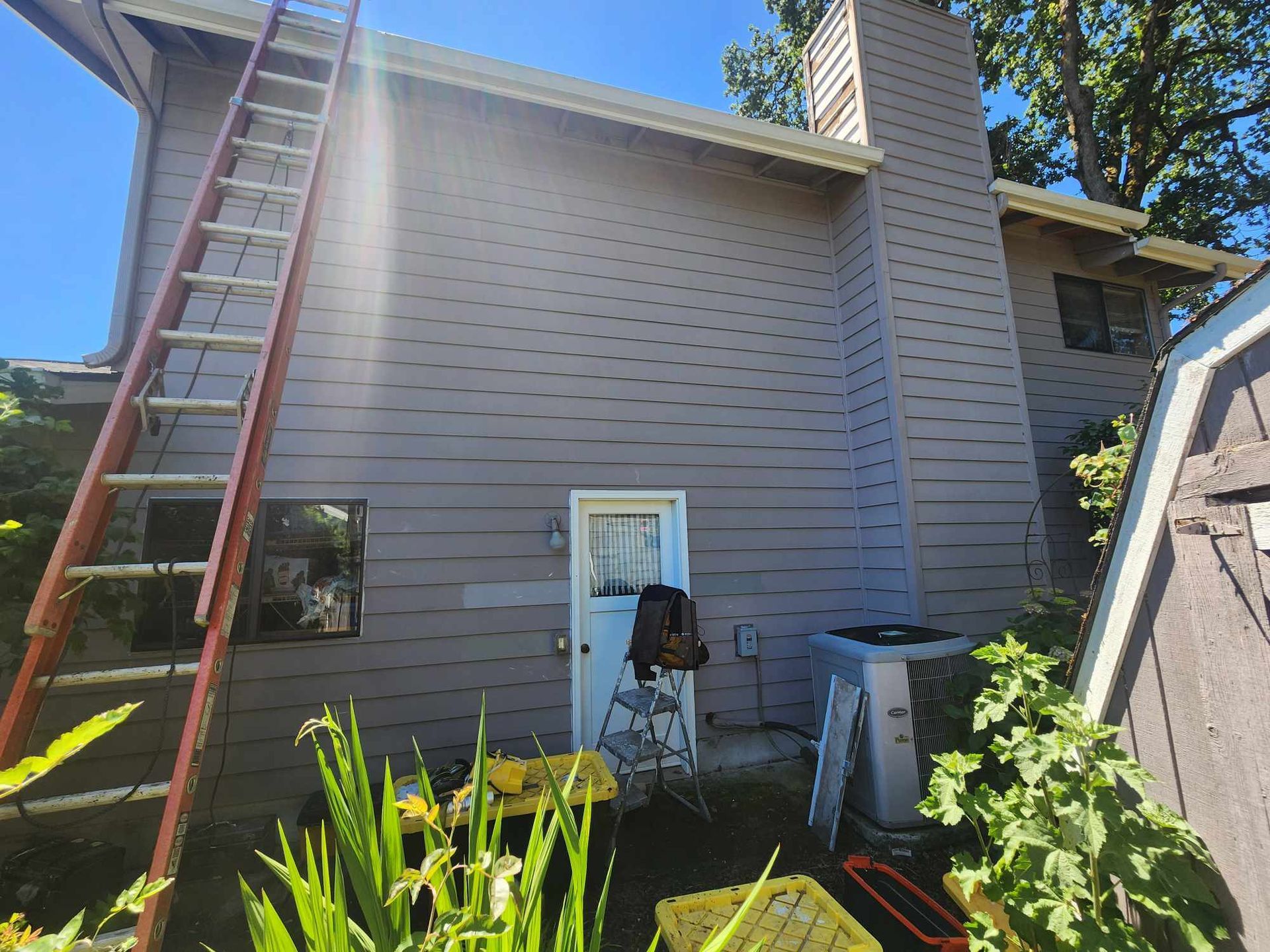 Exterior of a house with a tall ladder against the wall and a chimney rising above the roofline.