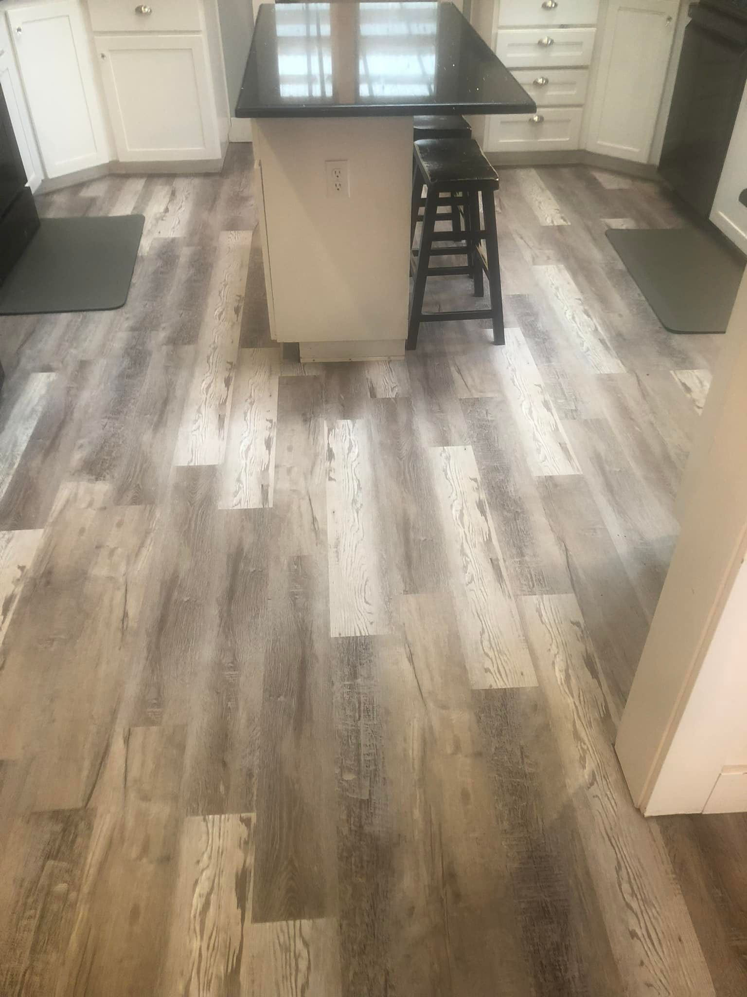 Kitchen with wood-look flooring and a dark island barstool in the center