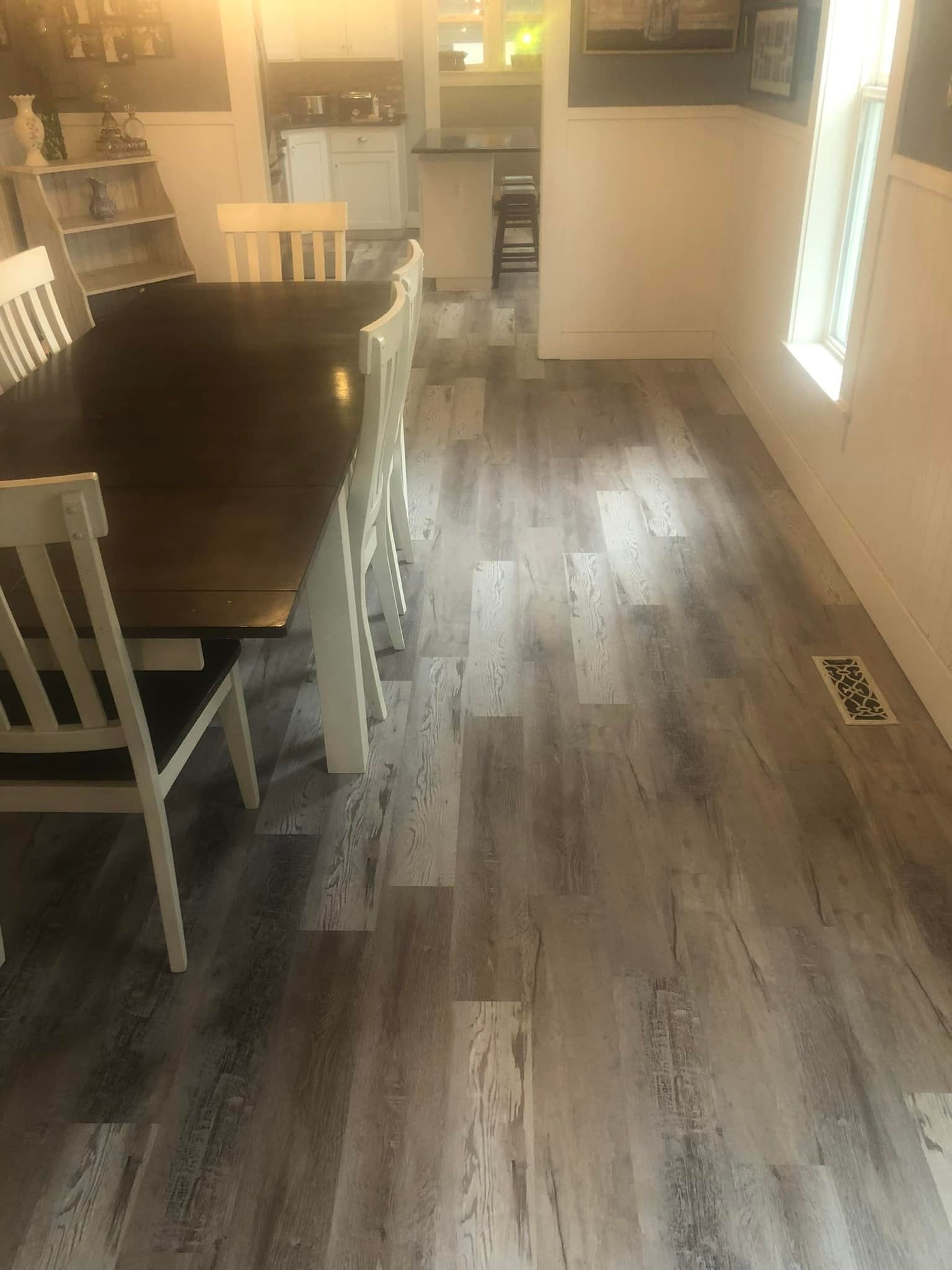 Dining room with dark table and chairs, light wood floor, and bright window light from the right.