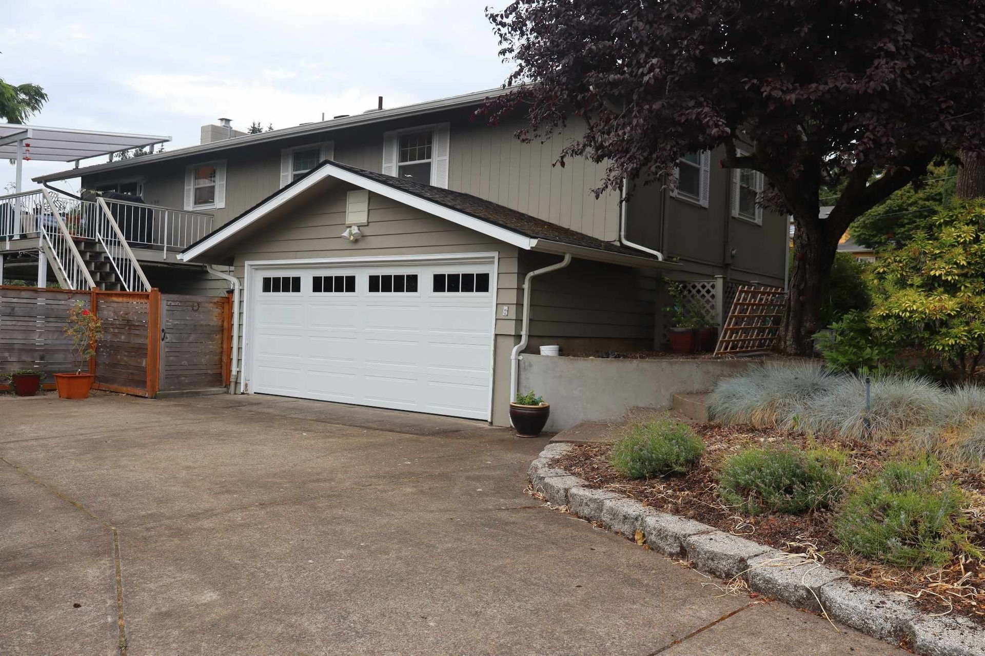 Suburban house with white garage, driveway, and landscaped front yard
