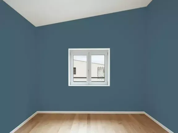 Empty blue room with wood floor and a small window centered on the far wall.