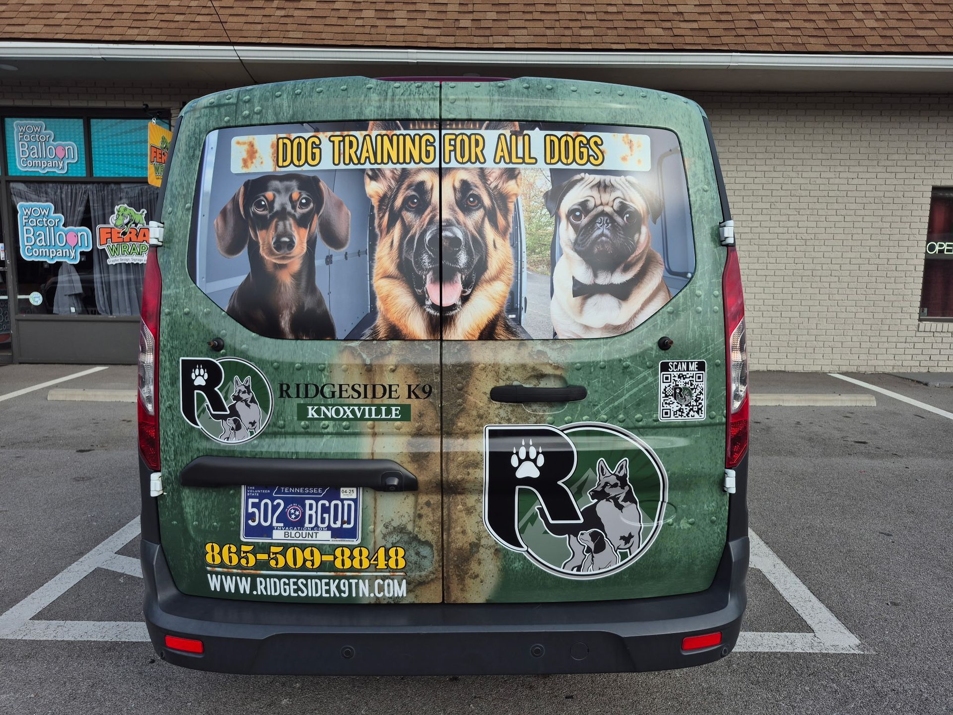 Dog training van with portraits of dogs, green wrap, phone number, and logo.