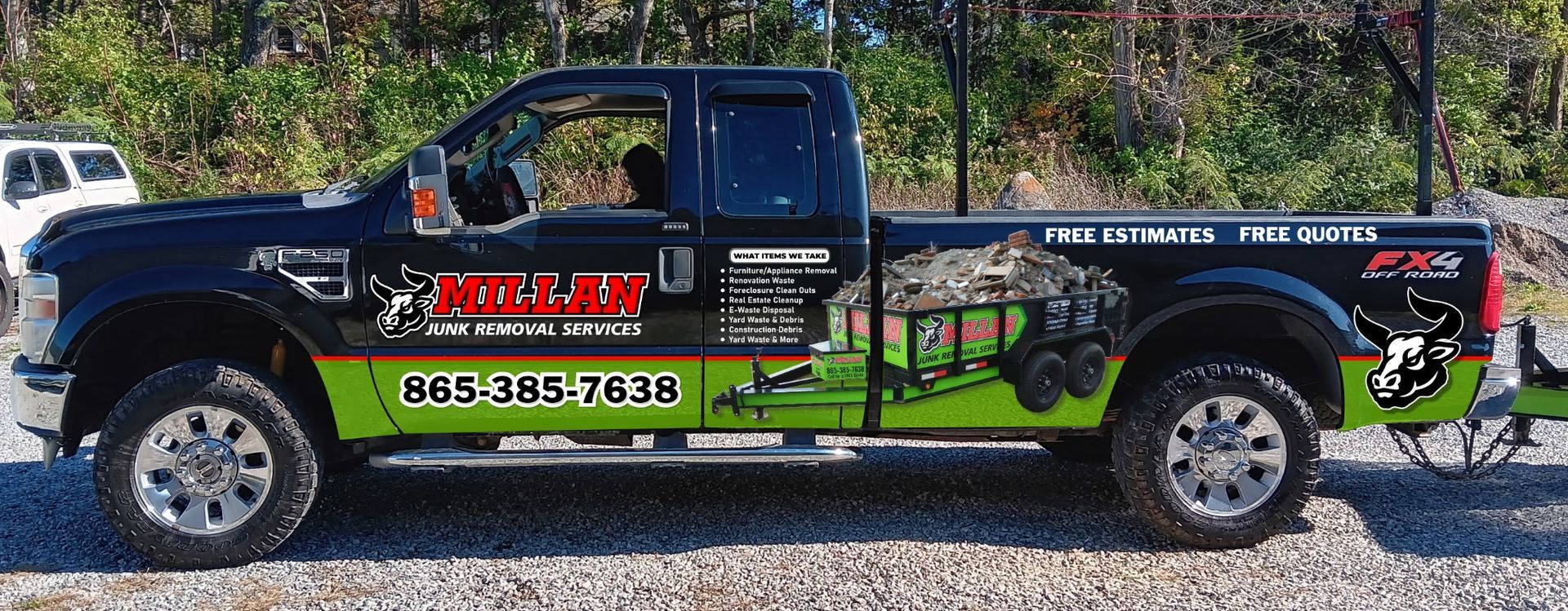 A black and green truck is parked in a gravel lot.
