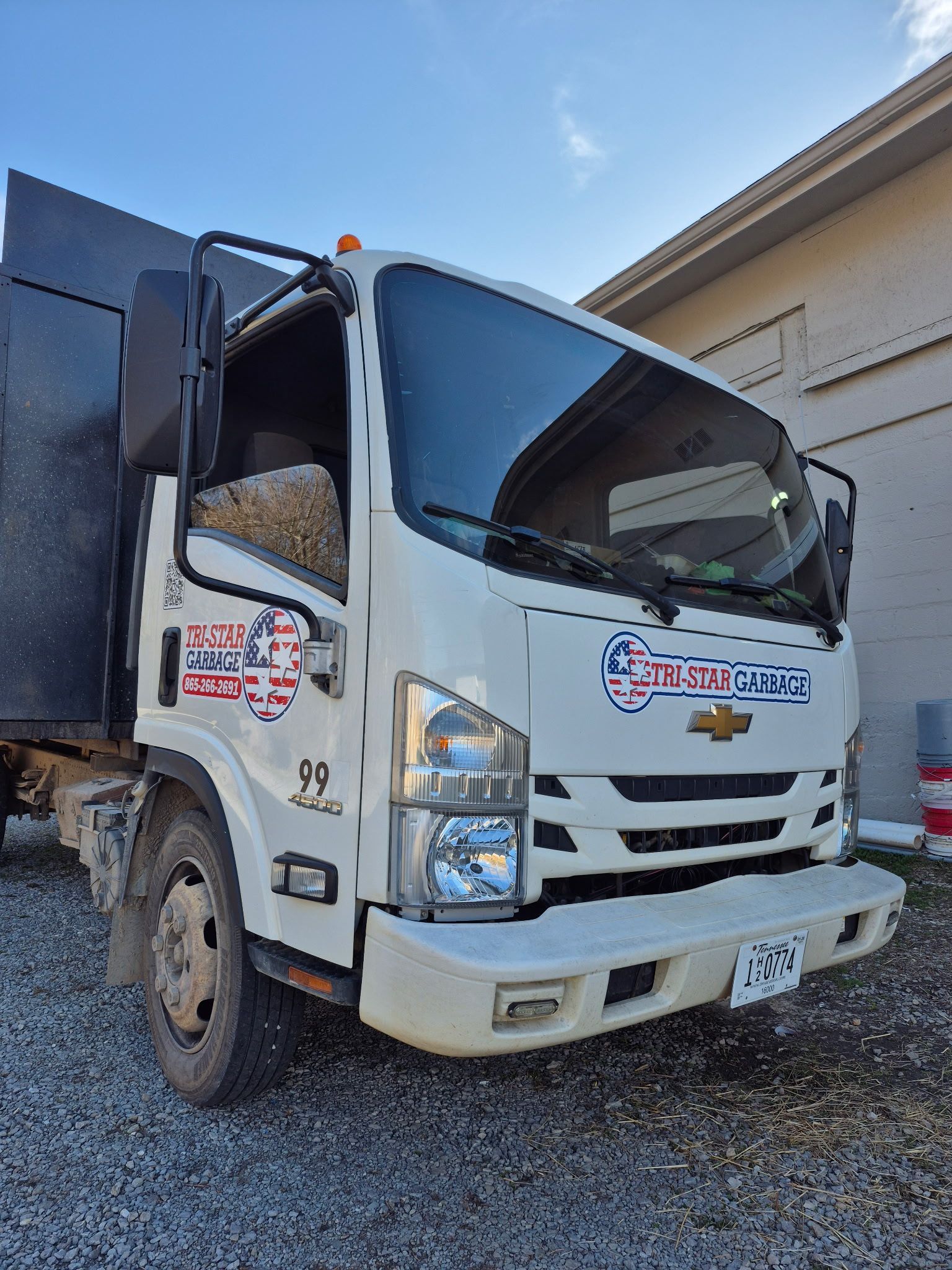 A white dump truck is parked in front of a building.