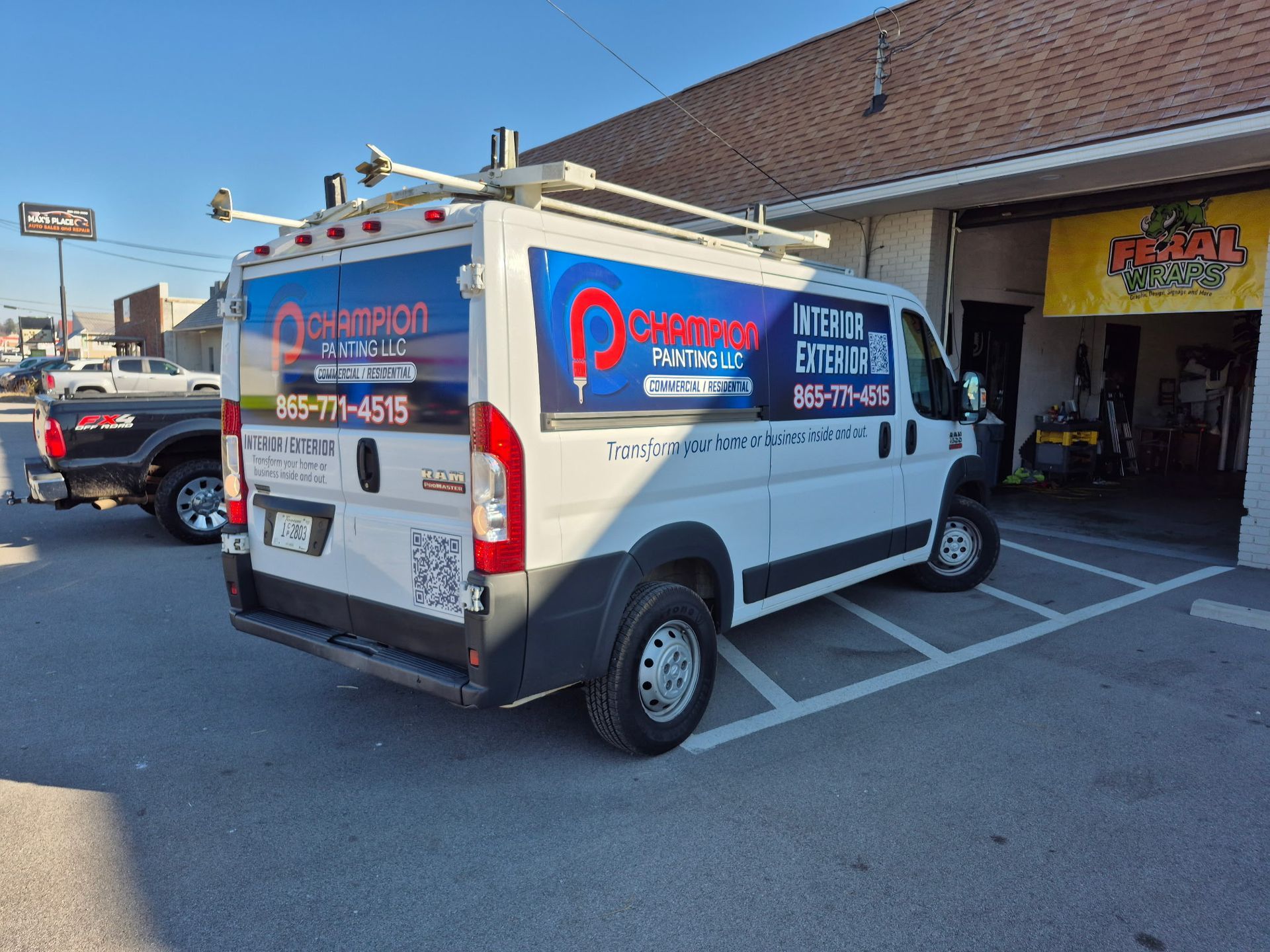 A white van is parked in a parking lot in front of a building.