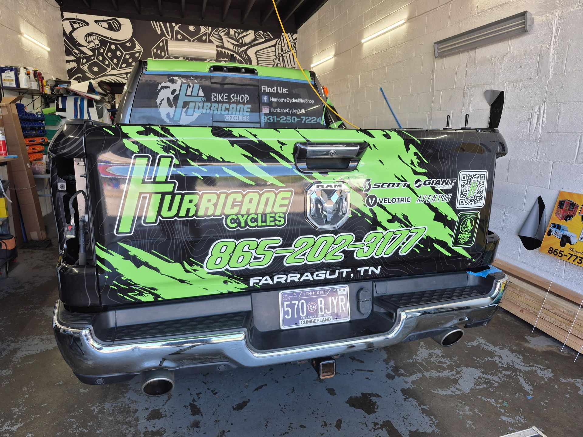 Black truck with green Hurricane Cycles logo, in a garage.