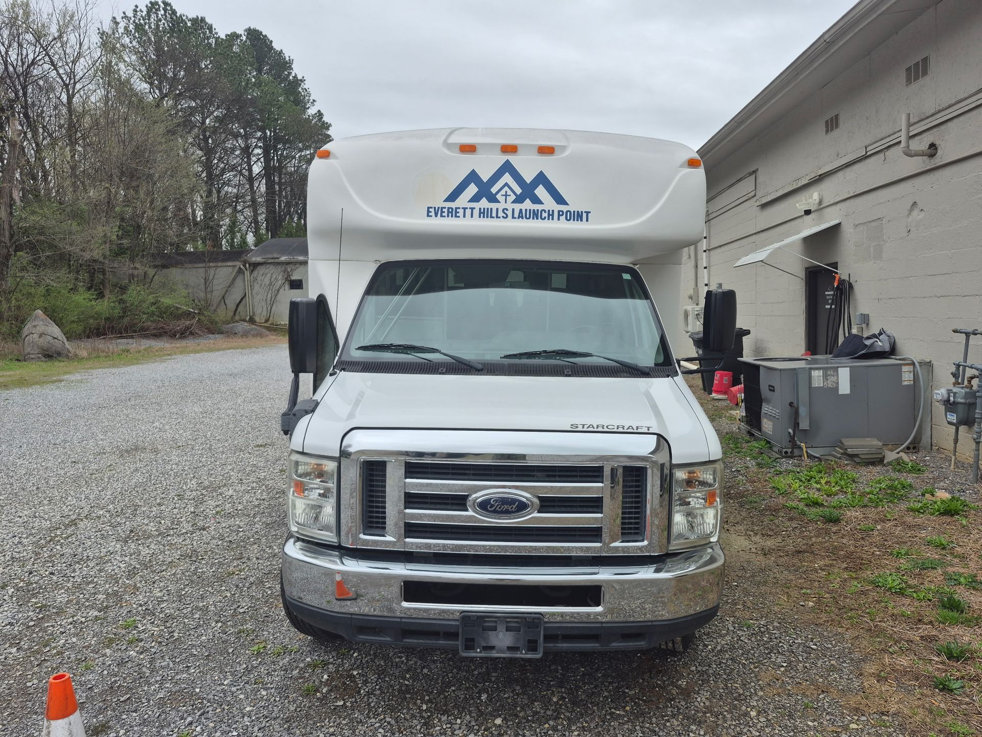 White Ford E-Series truck with attached cargo area, parked outside near a building.