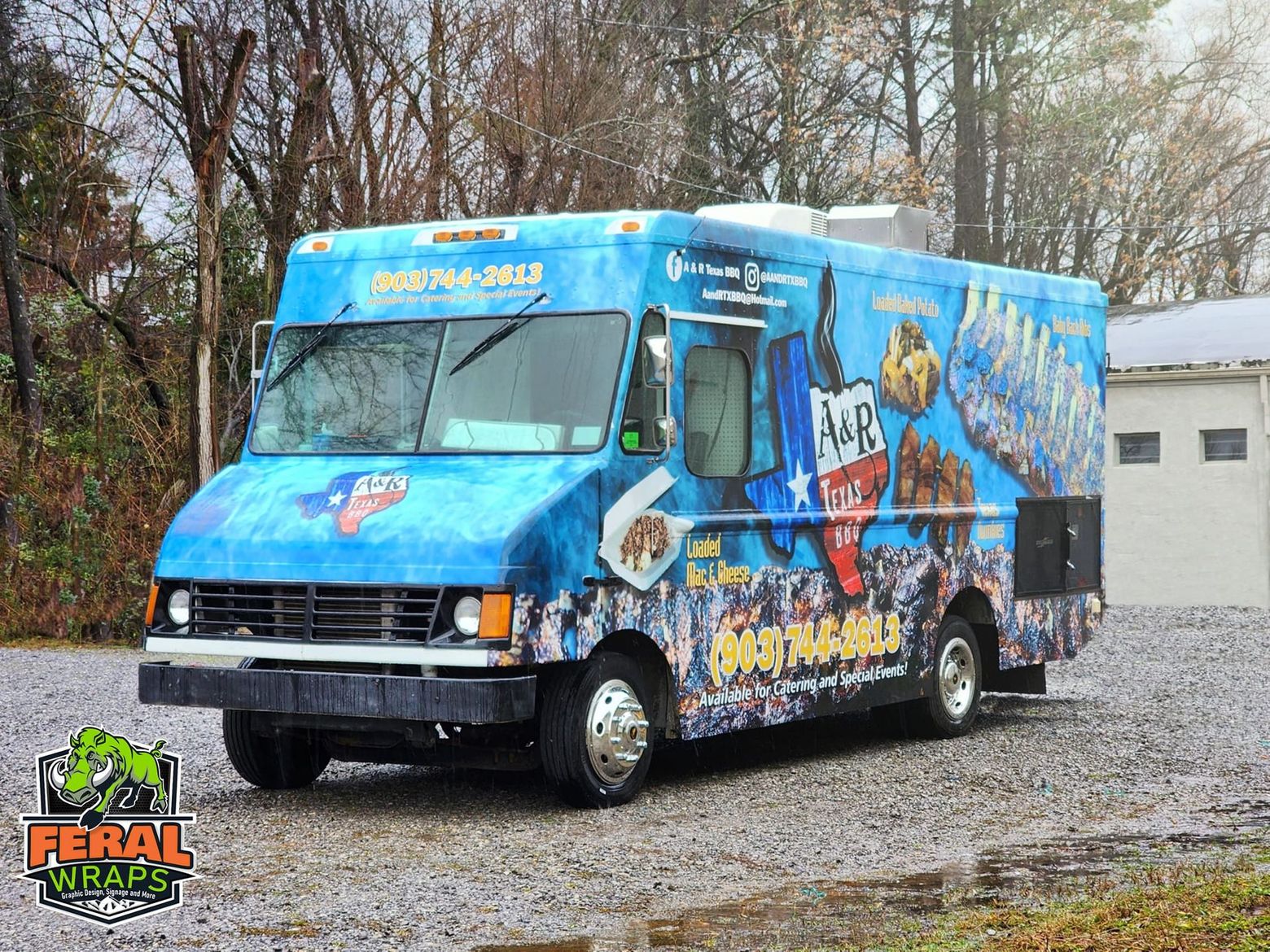 A blue food truck is parked in a gravel lot.