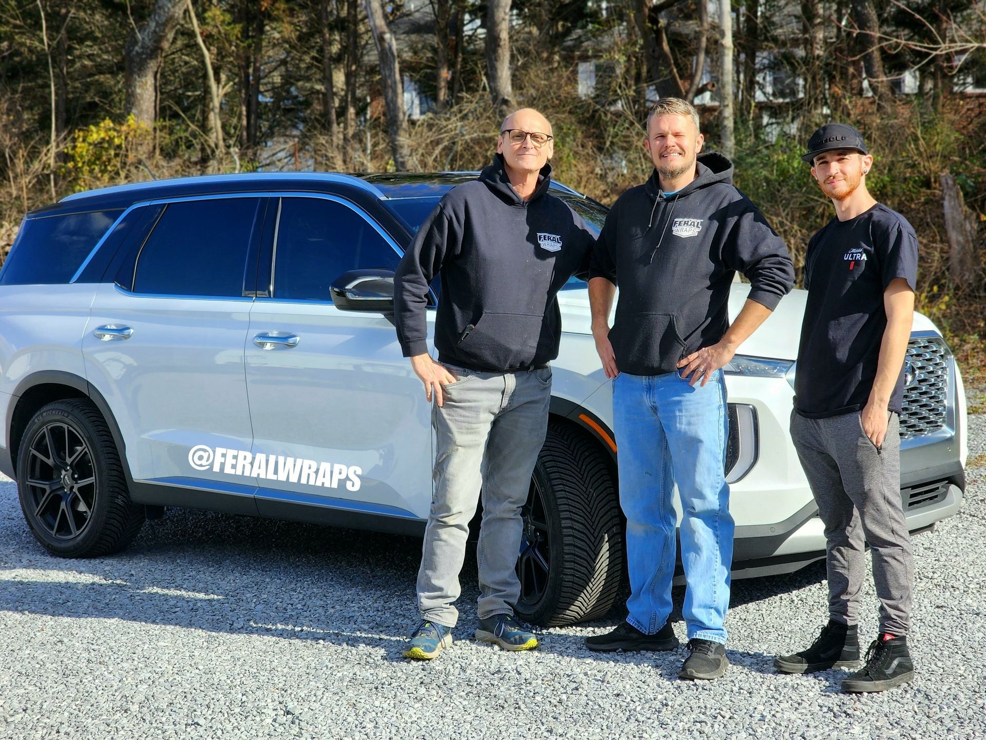 Three men are standing in front of a white suv.
