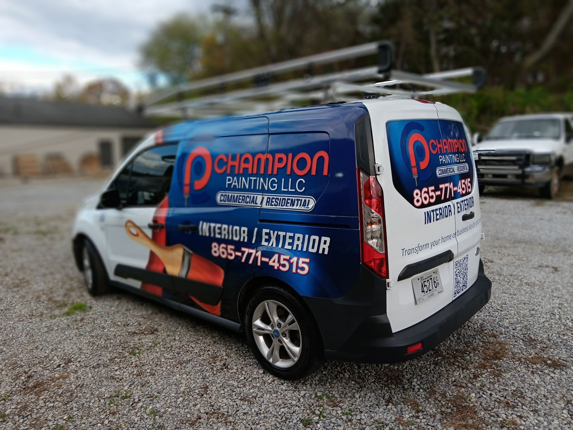 A champion painting llc van is parked in a gravel lot.