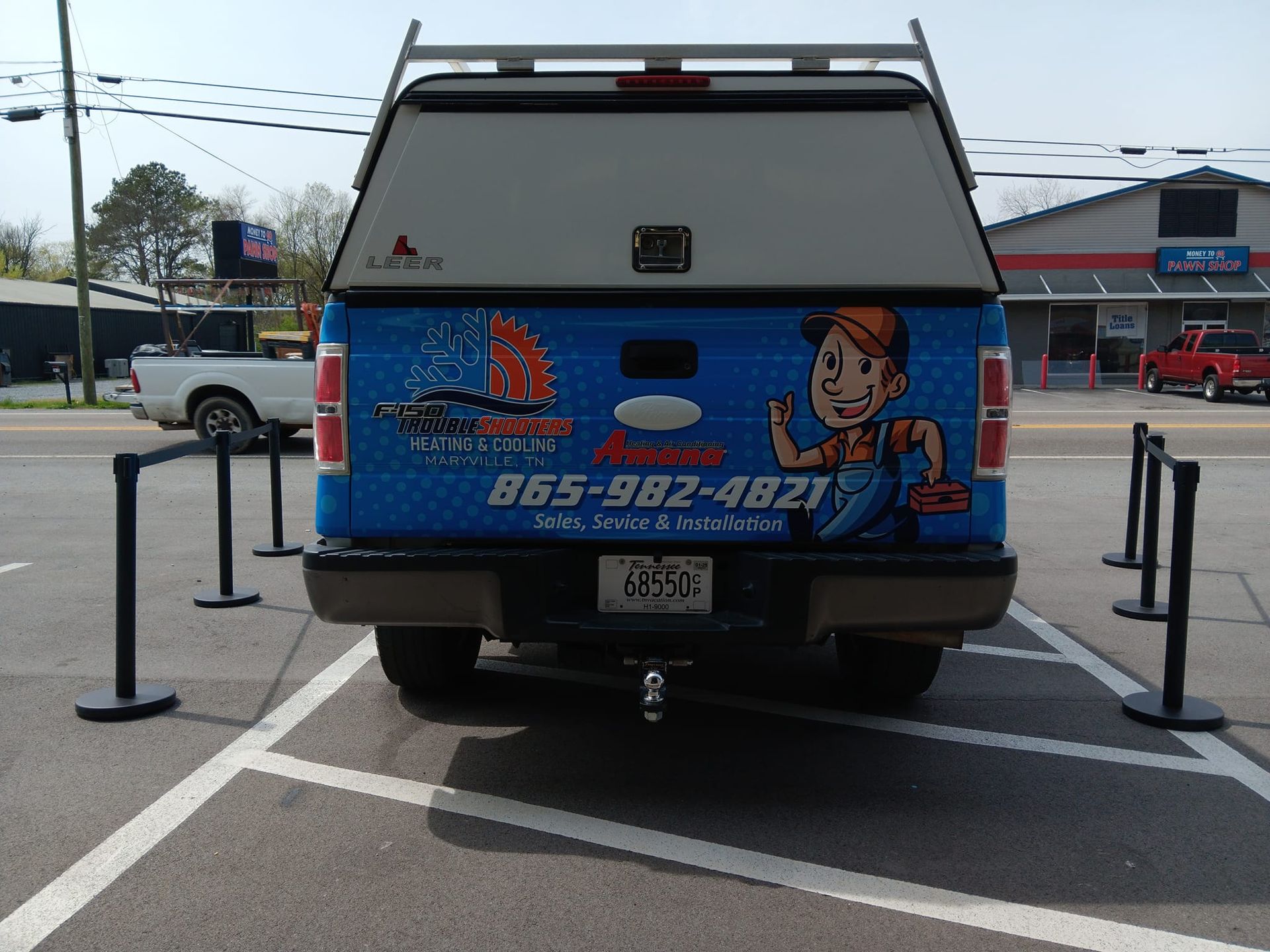 A blue truck with a plumber on the back is parked in a parking lot