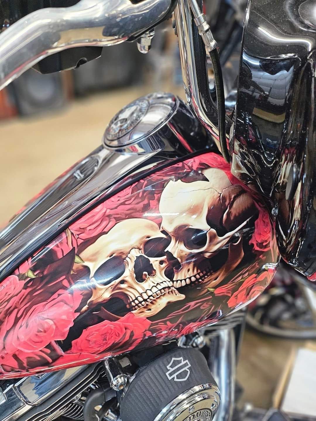 A motorcycle with a skull and roses painted on the tank.