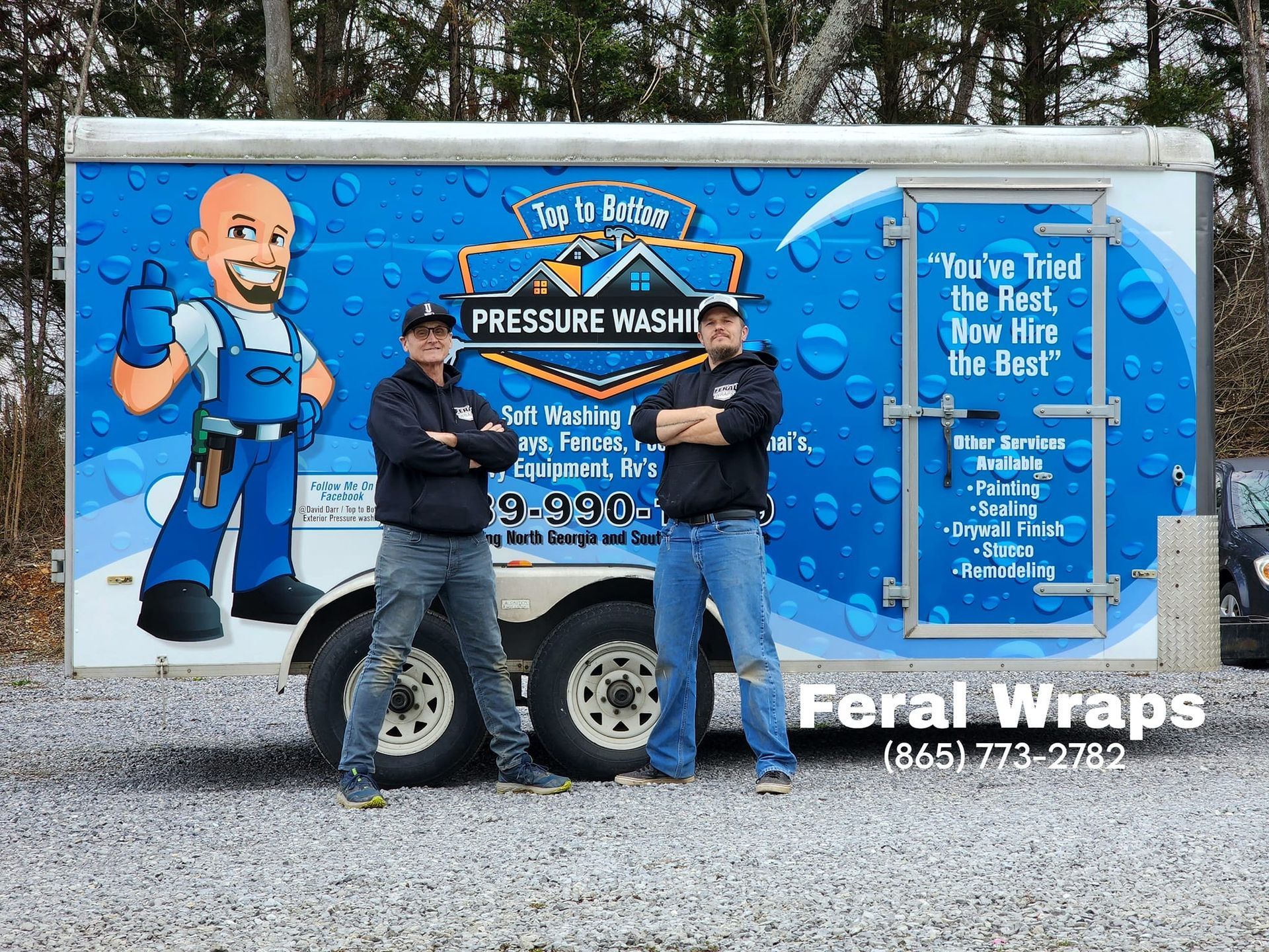 Two men are standing in front of a pressure washer trailer.