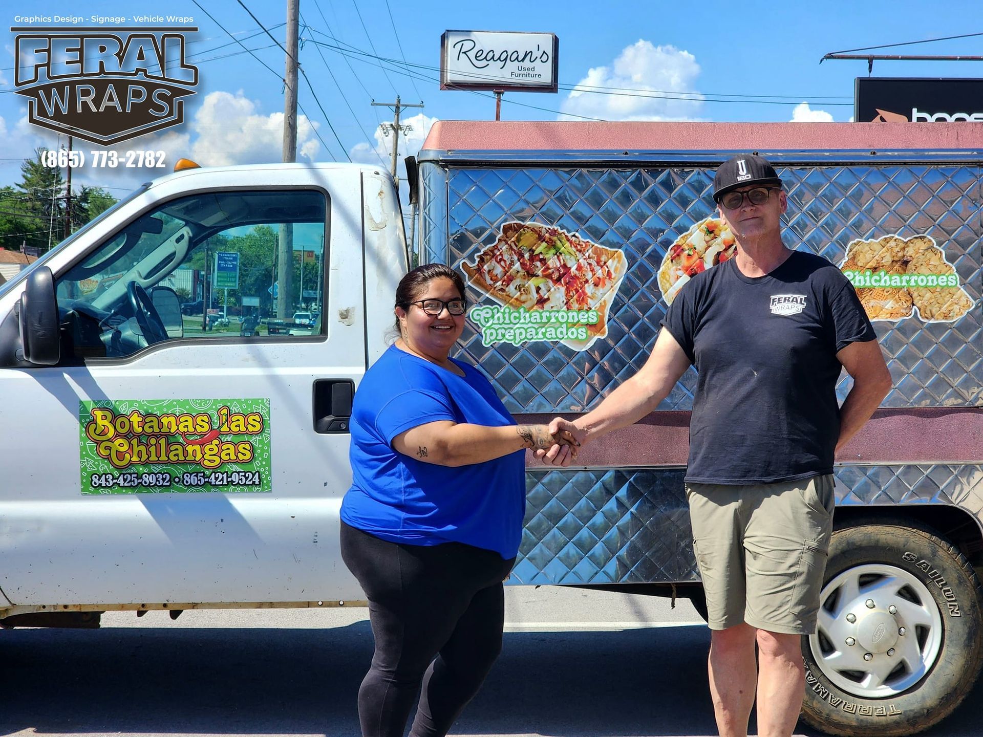 A man and a woman shaking hands in front of a food truck.