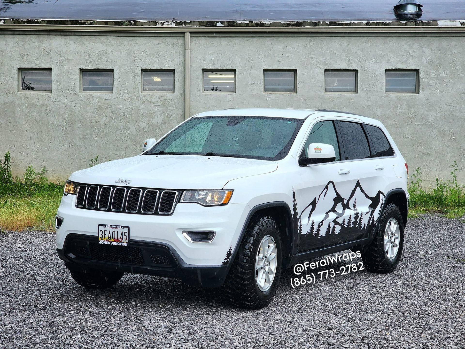 A white jeep grand cherokee is parked in front of a building.