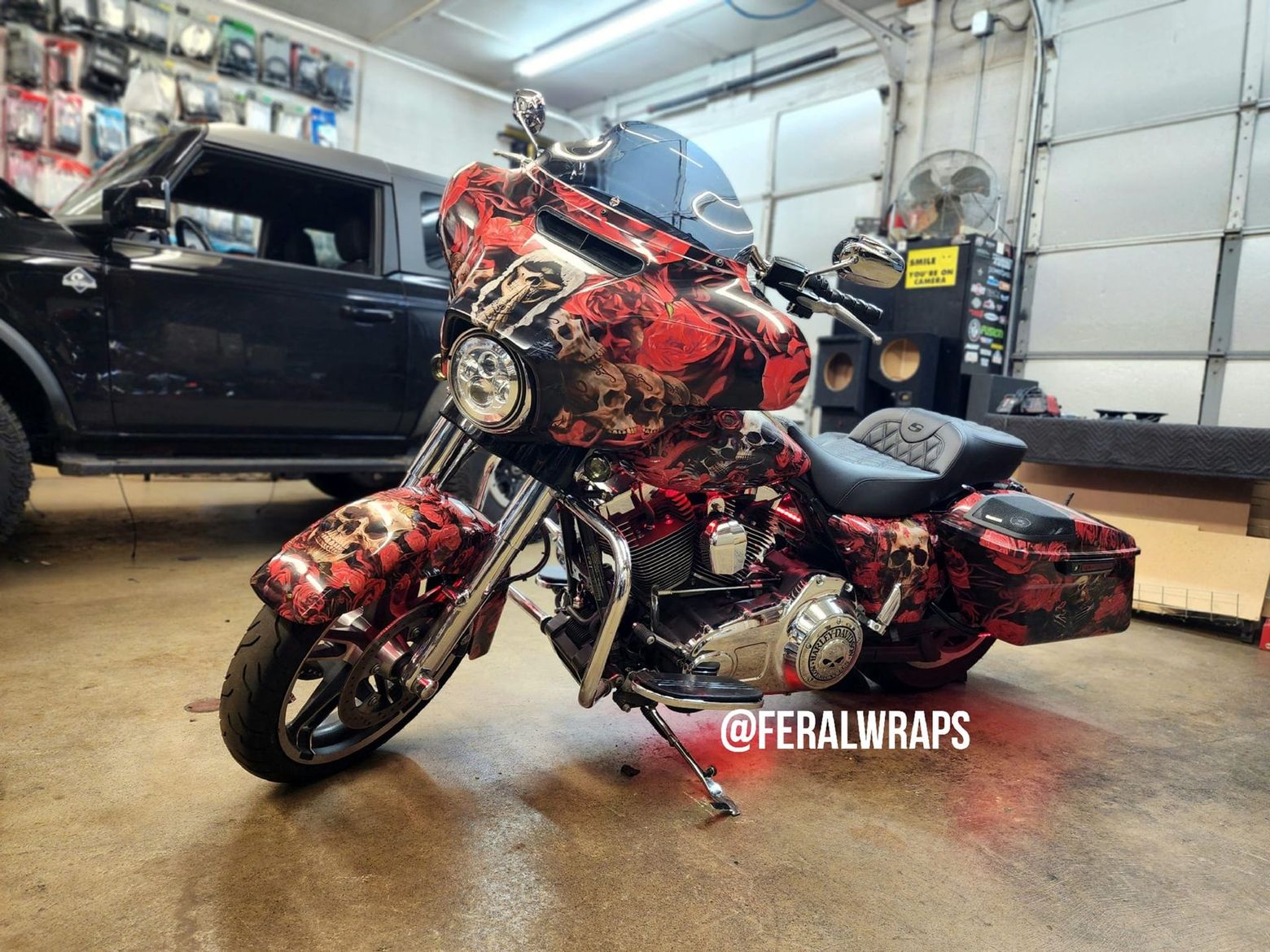 A red motorcycle is parked in a garage next to a black car.