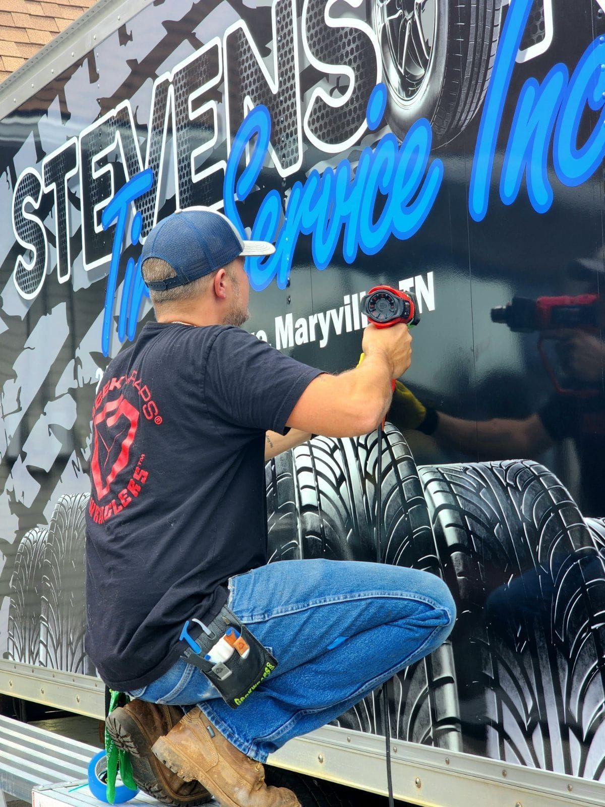 A man is working on the side of a stevens tire truck