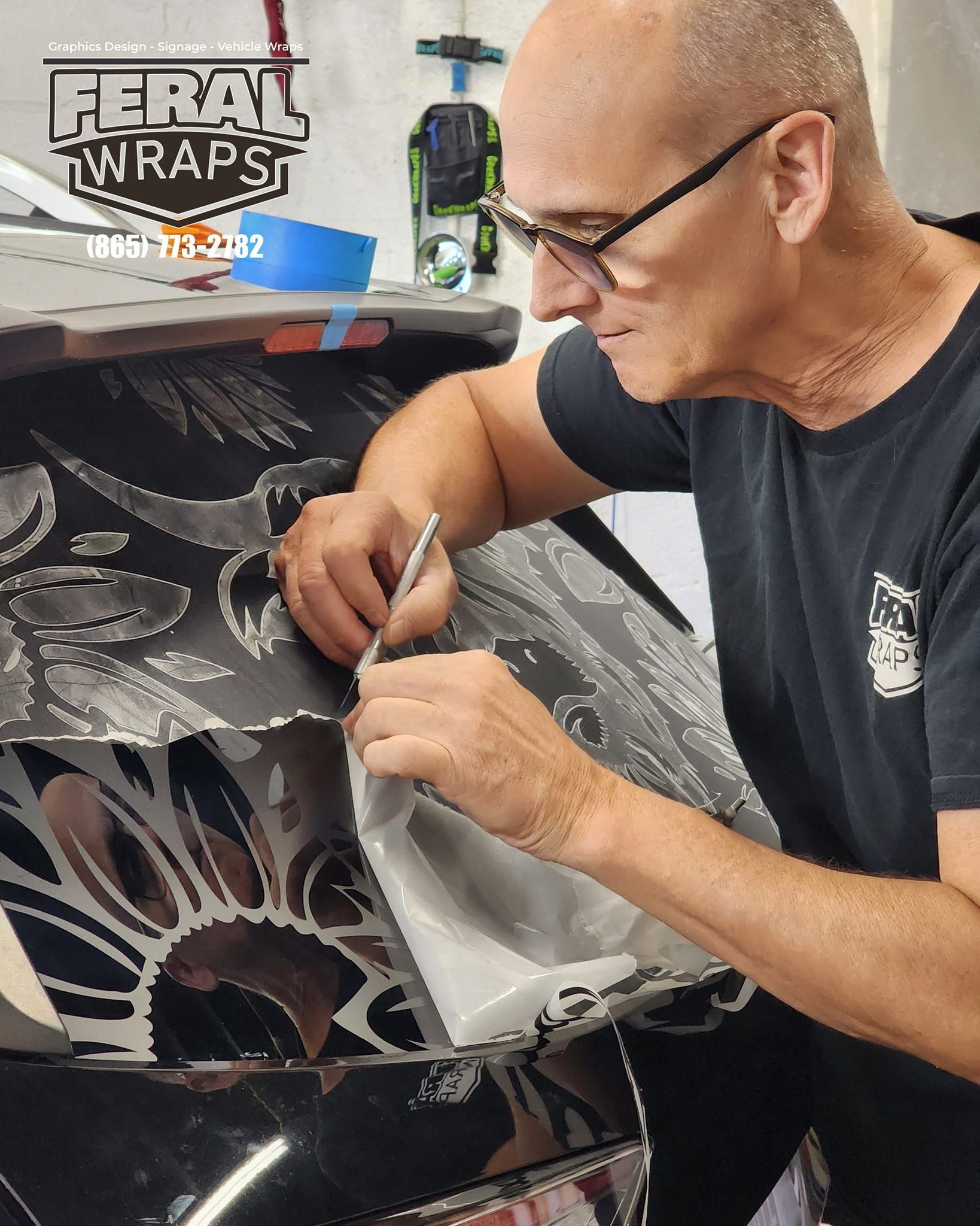 A man is working on a car with feral wraps written on the bottom