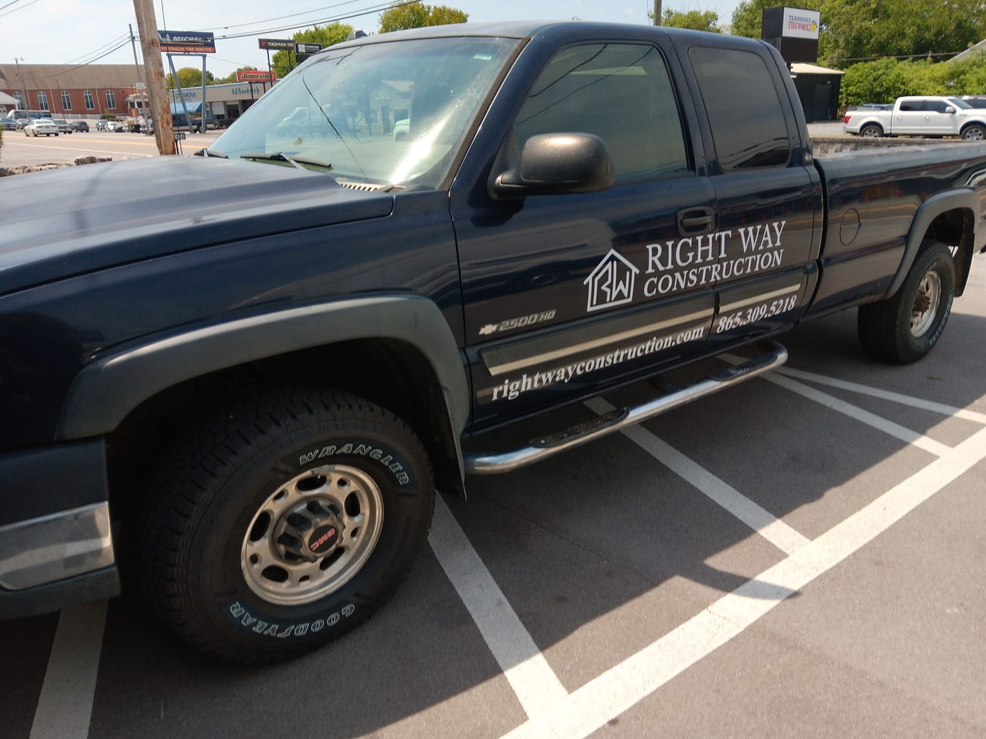 A black truck with right way construction written on the side is parked in a parking lot.