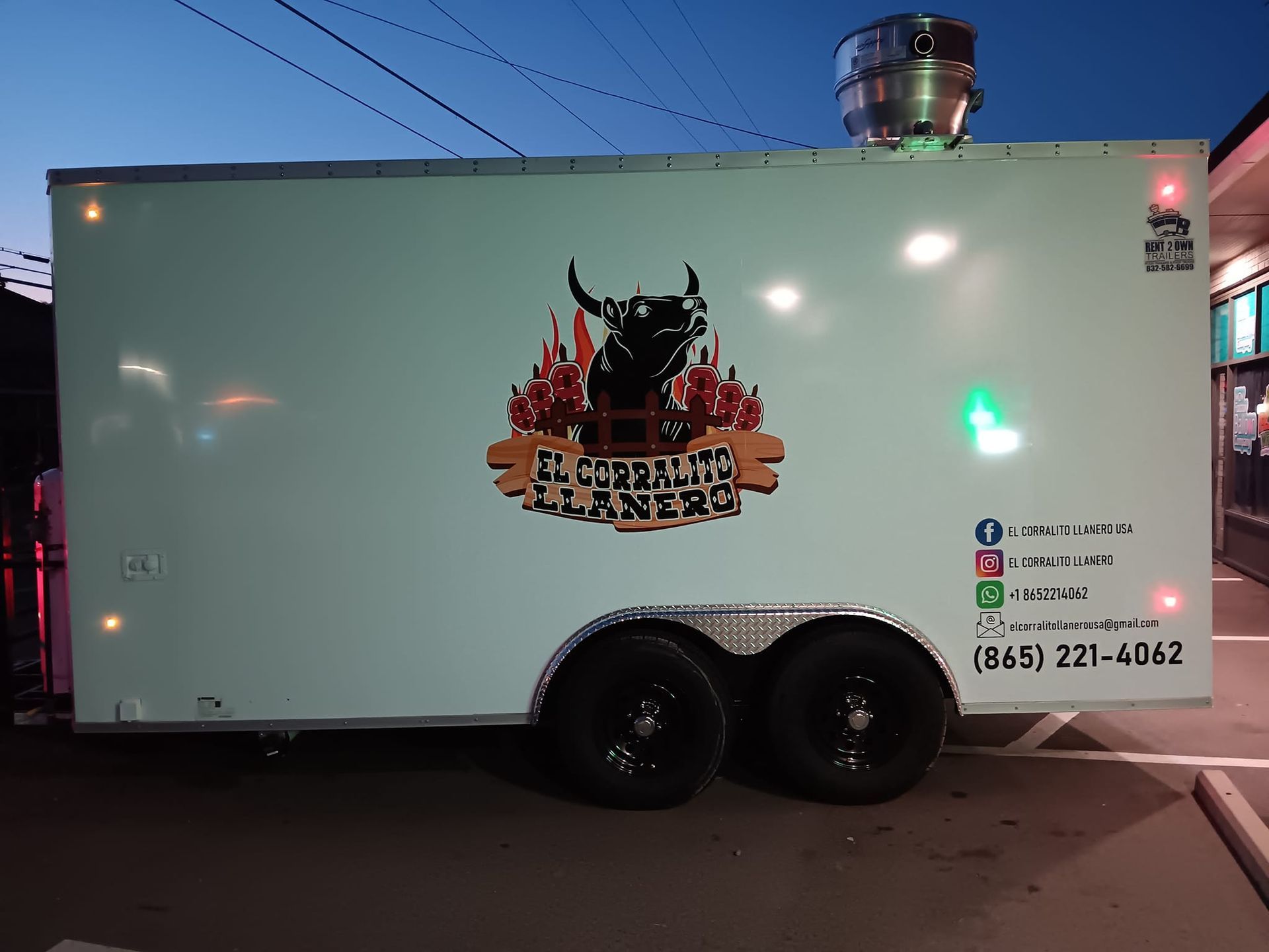A white trailer with a bull on it is parked in a parking lot.