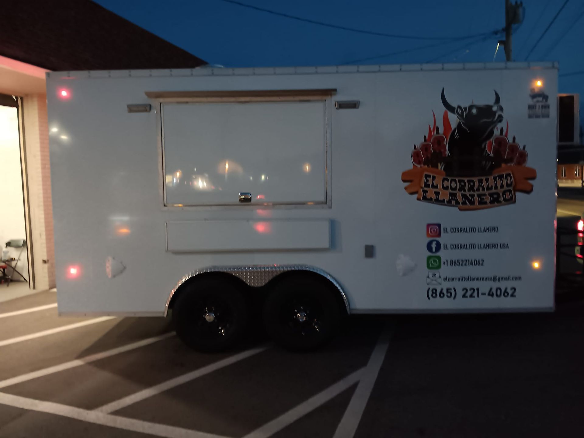 A white food truck is parked in a parking lot