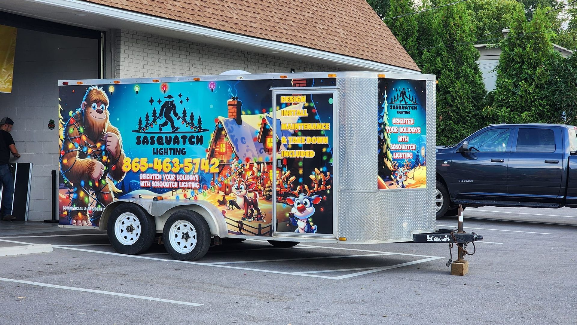 A trailer with a gorilla on it is parked in a parking lot next to a truck.