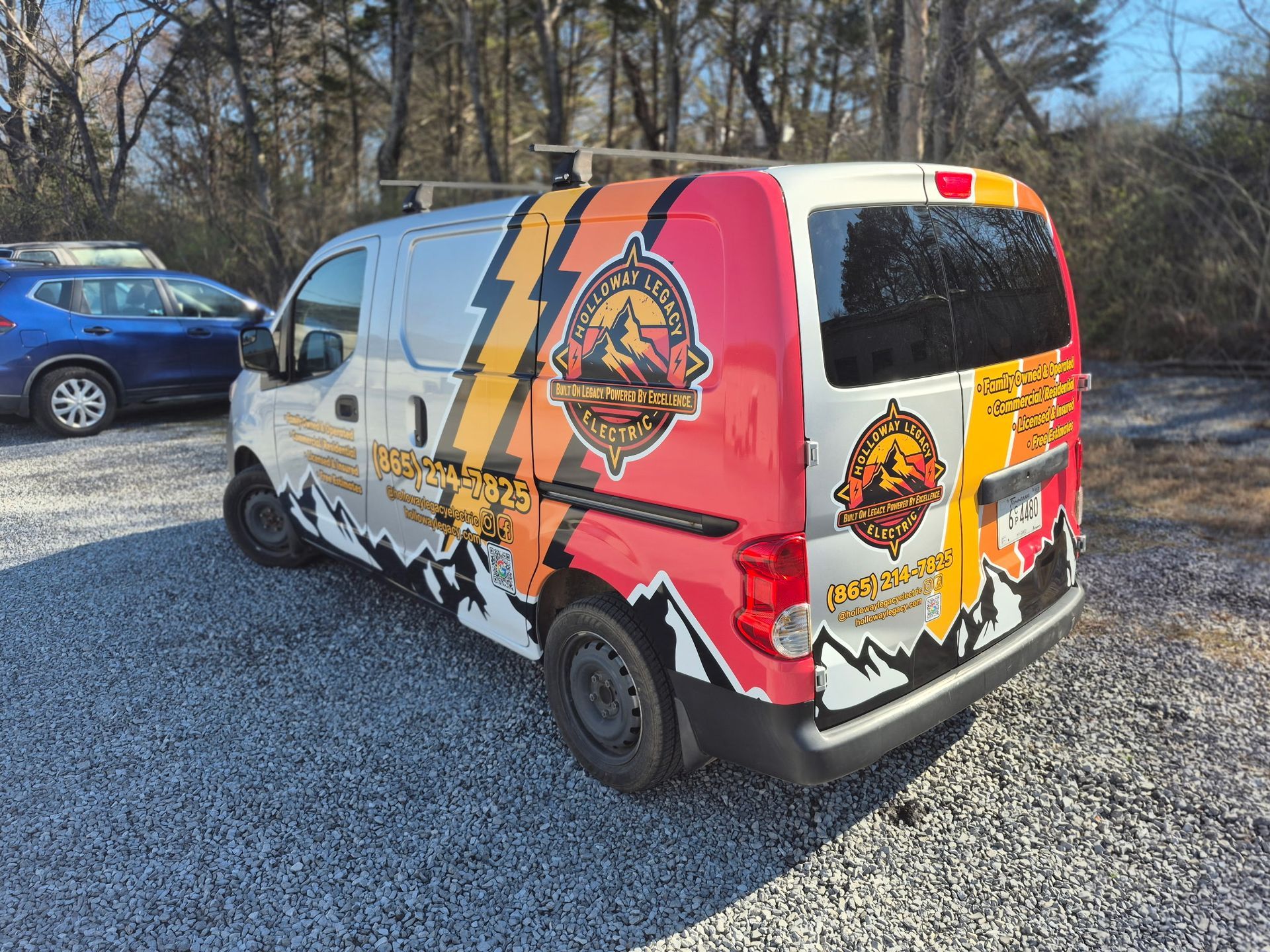 Van with company logo parked on gravel. Colorful graphics with mountains and lightning.